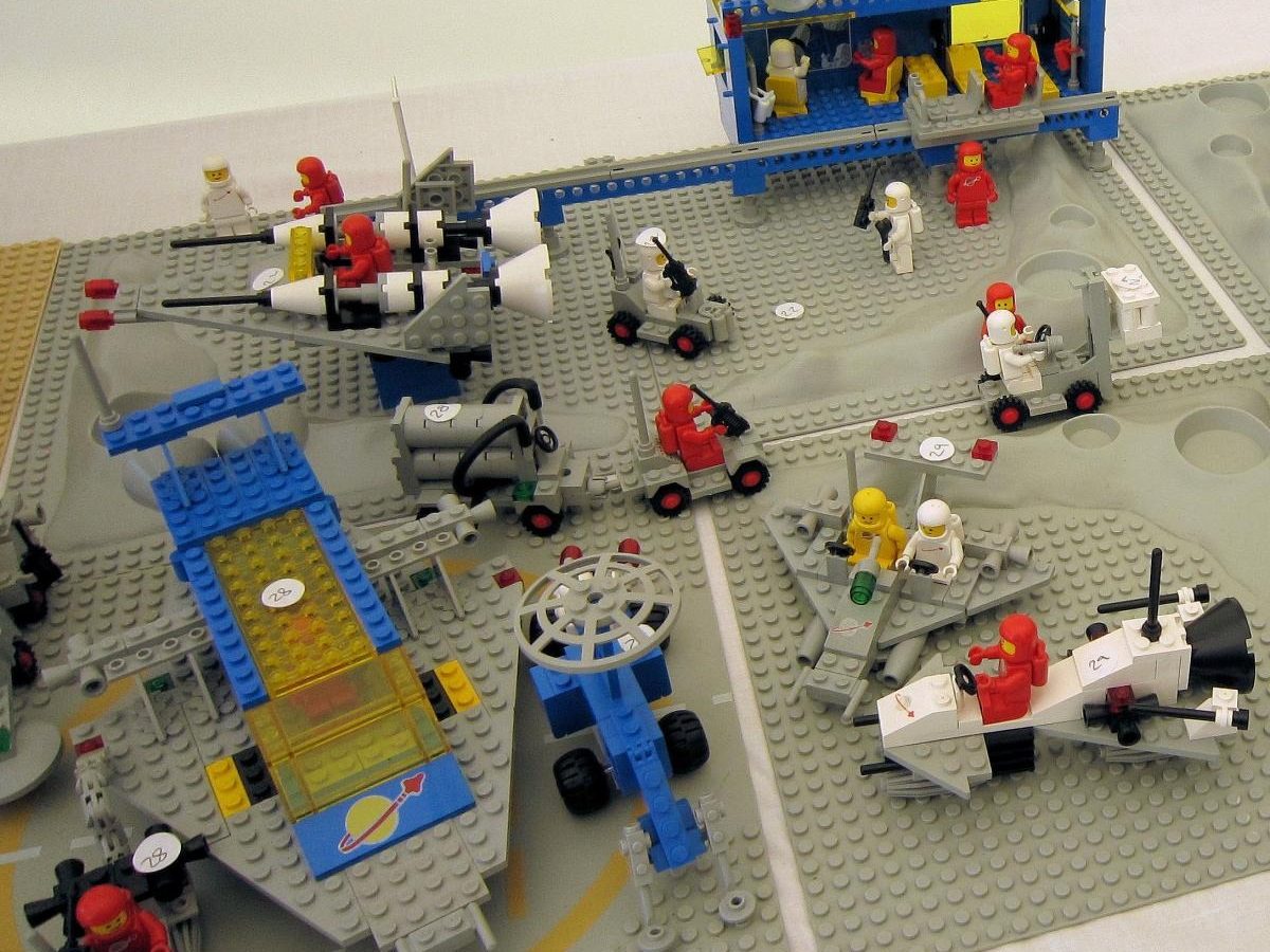 A Classic Space display on grey baseplates: a blue command base with radar dishes, rovers, a launcher and small spacecraft, with red and white astronauts